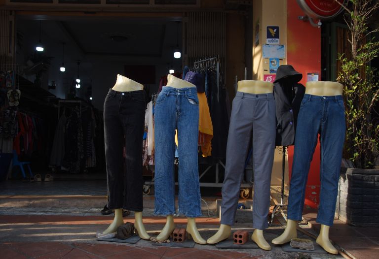 Headless mannequins in second-hand jeans on the pavement outside a Kampot thrift shop