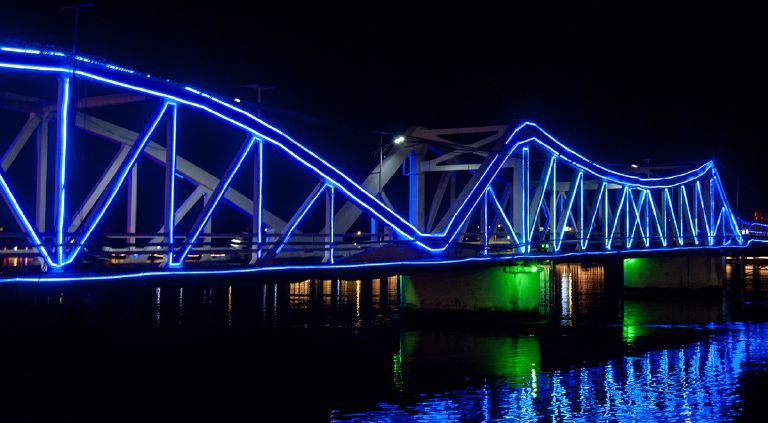 The old bridge in Kampot lit up with blue neon lights at night