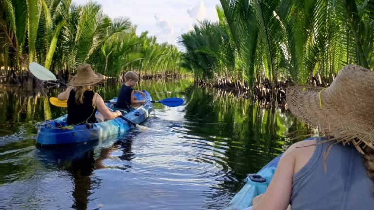 Kayaker gliding through the Green Cathedral mangrove tunnel near Kampot.